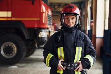Female firefighter in protective uniform standing near truck.