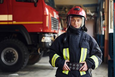Female firefighter in protective uniform standing near truck.