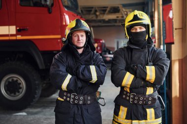 Koruyucu üniformalı erkek ve kadın itfaiyeciler bir arada duruyorlar..