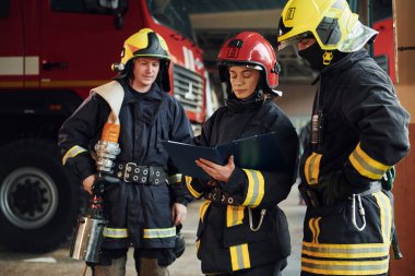 Not defteriyle. İstasyondaki bir grup koruyucu üniformalı itfaiyeci....