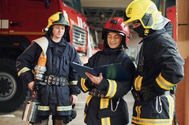 Not defteriyle. İstasyondaki bir grup koruyucu üniformalı itfaiyeci....