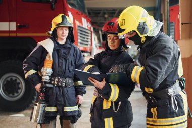 Not defteriyle. İstasyondaki bir grup koruyucu üniformalı itfaiyeci....