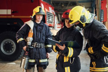 Not defteriyle. İstasyondaki bir grup koruyucu üniformalı itfaiyeci....