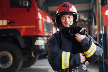 Şirin siyah kedi. Koruyucu üniformalı kadın itfaiyeci kamyonun yanında duruyor..