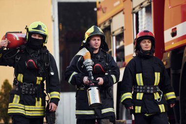Dışarıdaki kamyonun yanında koruyucu üniformalı bir grup itfaiyeci..