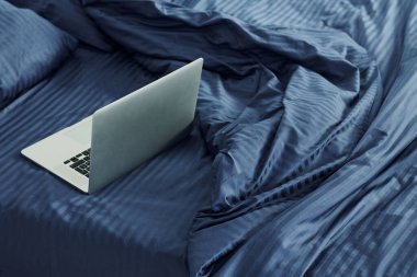 Laptop yatağın üstünde. Gündüz vakti güzel, modern yatak odasının iç tasarımı ve tasarımı..