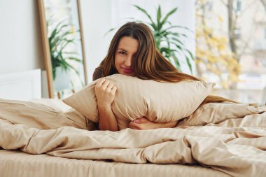 Güzel genç bir kadın yatakta dinleniyor. Gündüz vakti güzel, modern yatak odasının iç tasarımı ve tasarımı..