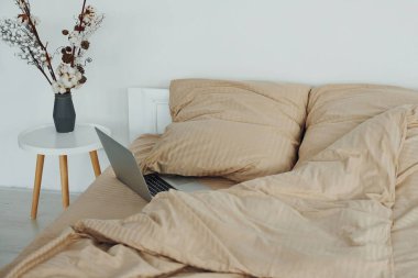 Laptop yatağın üstünde. Gündüz vakti güzel, modern yatak odasının iç tasarımı ve tasarımı..