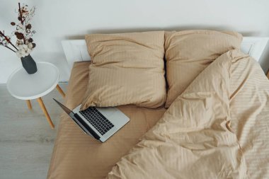 Laptop yatağın üstünde. Gündüz vakti güzel, modern yatak odasının iç tasarımı ve tasarımı..