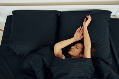 Top view og woman that lying down on bed. Interior and design of beautiful modern bedroom at daytime.