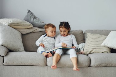 Kız ve erkek kardeş kitap okuyor. Gündüz vakti güzel, modern yatak odasının iç tasarımı ve tasarımı..