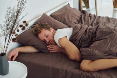 Adam yatakta uyuyor. Gündüz vakti güzel, modern yatak odasının iç tasarımı ve tasarımı..