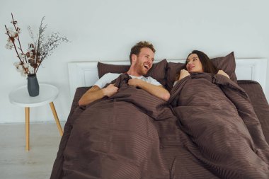 Yatağa uzanmış tatlı bir çift. Gündüz vakti güzel, modern yatak odasının iç tasarımı ve tasarımı..