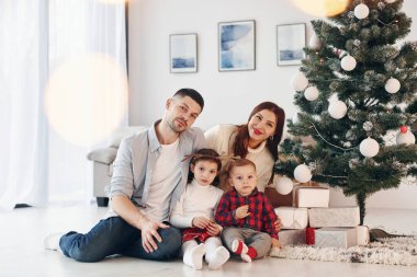 Köknara karşı oturuyor. Güzel bir aile evde yeni yılı ve Noel 'i kutlar..