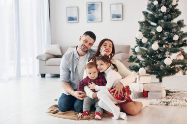 Köknara karşı oturuyor. Güzel bir aile evde yeni yılı ve Noel 'i kutlar..