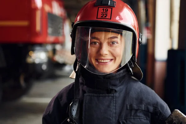 Close up view. Female firefighter in protective uniform standing near truck.