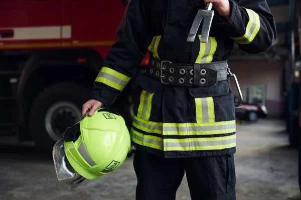 Male firefighter in protective uniform standing near truck.