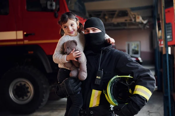 Trzyma Pluszowego Misia Happy Little Girl Jest Męskim Strażakiem Mundurze — Zdjęcie stockowe