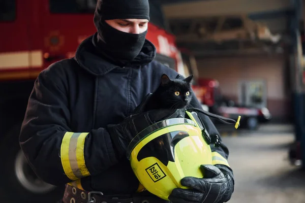 身穿防护服的消防员的画像 上面有可爱的小黑猫 — 图库照片