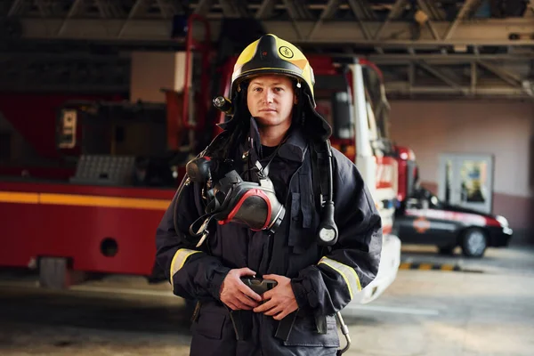 Female firefighter in protective uniform standing near truck.