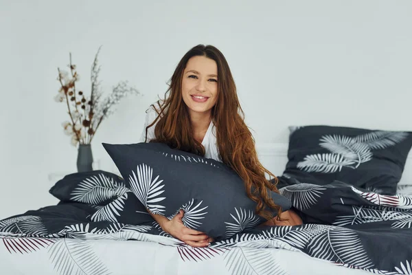 Yatakta rahat ve mutlu bir kadın görüyorum. Gündüz vakti güzel, modern yatak odasının iç tasarımı ve tasarımı..