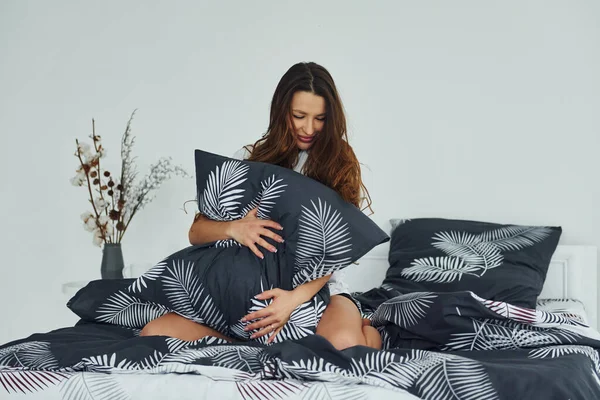 Yatakta rahat ve mutlu bir kadın görüyorum. Gündüz vakti güzel, modern yatak odasının iç tasarımı ve tasarımı..