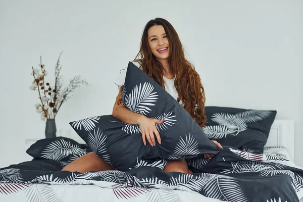 Yatakta rahat ve mutlu bir kadın görüyorum. Gündüz vakti güzel, modern yatak odasının iç tasarımı ve tasarımı..