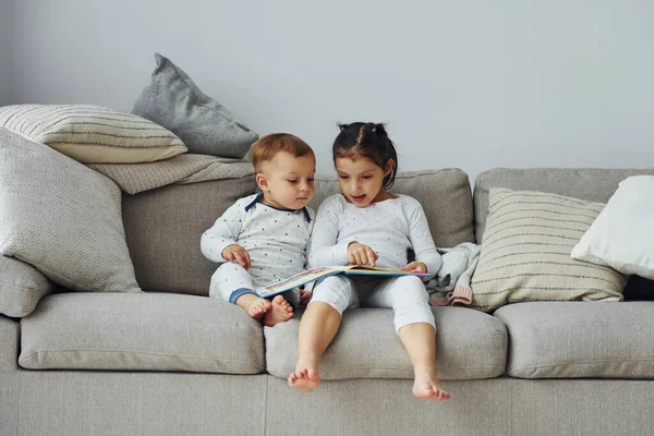 Kız ve erkek kardeş kitap okuyor. Gündüz vakti güzel, modern yatak odasının iç tasarımı ve tasarımı..