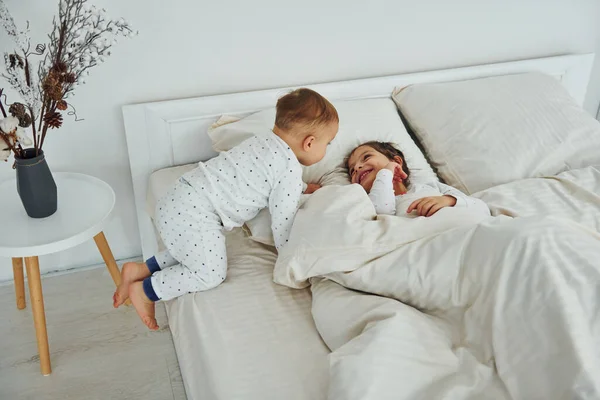 两个孩子躺在床上玩得很开心 白天漂亮的现代卧房的室内设计 — 图库照片