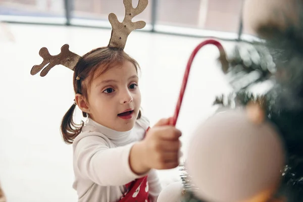 Cute Little Girl Stoi Nowy Rok Drzewo Cukierkami Ręku — Zdjęcie stockowe
