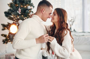 Ellerinde maytaplarla. Genç romantik çift yeni yılı içeride kutluyor..