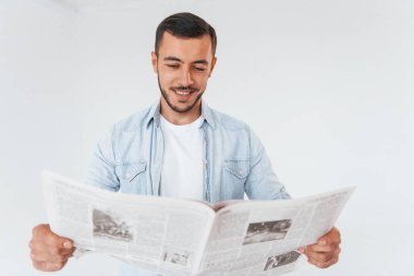 Gazete okuyor. Beyaz arka planda duran yakışıklı genç adam..