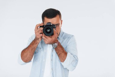 Profesyonel kamerayla. Beyaz arka planda duran yakışıklı genç adam..