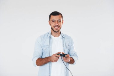 joystick 'i elinde tutuyor. Beyaz arka planda duran yakışıklı genç adam..