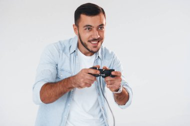 joystick 'i elinde tutuyor. Beyaz arka planda duran yakışıklı genç adam..