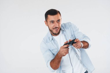 joystick 'i elinde tutuyor. Beyaz arka planda duran yakışıklı genç adam..
