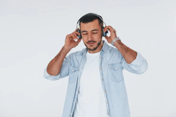 Listens Music Headphones Young Handsome Man Standing Indoors White Background — Fotografia de Stock