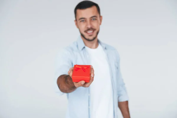 Holds Red Gift Box Young Handsome Man Standing Indoors White — Stockfoto