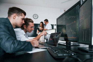 Detaylara dikkat et. Borsacılardan oluşan bir ekip modern ofiste birçok ekran ekranı ile çalışır..