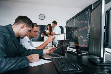 Detaylara dikkat et. Borsacılardan oluşan bir ekip modern ofiste birçok ekran ekranı ile çalışır..