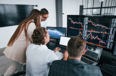 Grafikleri takip ediyor. Borsacılardan oluşan bir ekip modern ofiste birçok ekran ekranı ile çalışır..