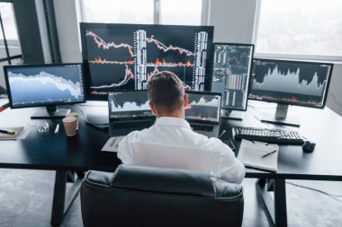 Ofiste çalışan genç borsacıların arka görüntüsü. Ekranların çoğu.