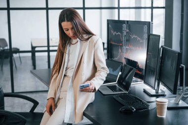 Genç bayan borsacı ofisin içinde. Ekranların çoğu.