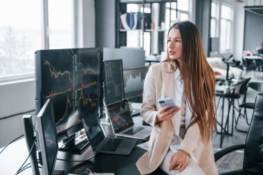 Genç bayan borsacı ofisin içinde. Ekranların çoğu.