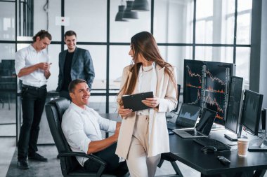 Resmi olarak genç bir kadın insanların önünde giyinir. Borsacılardan oluşan bir ekip modern ofiste birçok ekran ekranı ile çalışır..