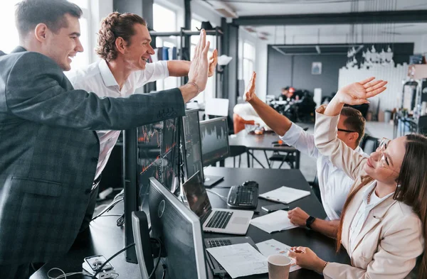 Çak bir beşlik. Borsacılardan oluşan bir ekip modern ofiste birçok ekran ekranı ile çalışır..