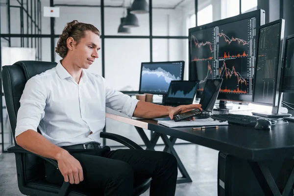 Genç borsacı erkek ofis içinde çalışıyor. Ekranların çoğu.