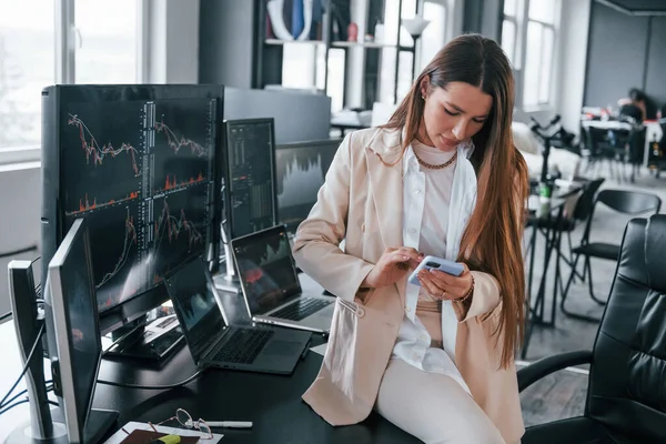 Genç bayan borsacı ofisin içinde. Ekranların çoğu.