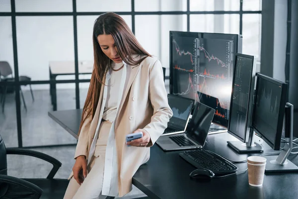 Genç bayan borsacı ofisin içinde. Ekranların çoğu.