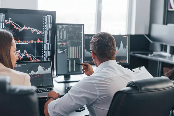 Borsacılardan oluşan bir ekip modern ofiste birçok ekran ekranı ile çalışır..